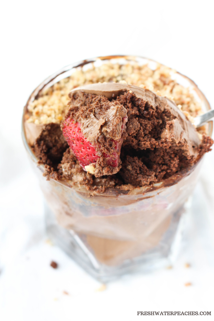 Spoon inside paleo chocolate trifle cup with strawberry on top.