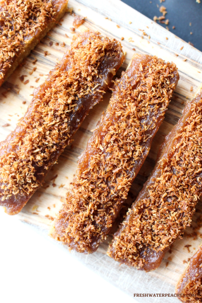 Caramel Coconut Candy Bars on wooden cutting board.