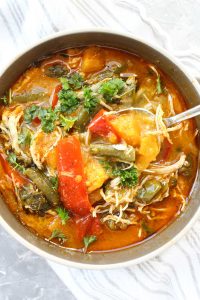 Bowl of red curry soup with spoon dipped inside.
