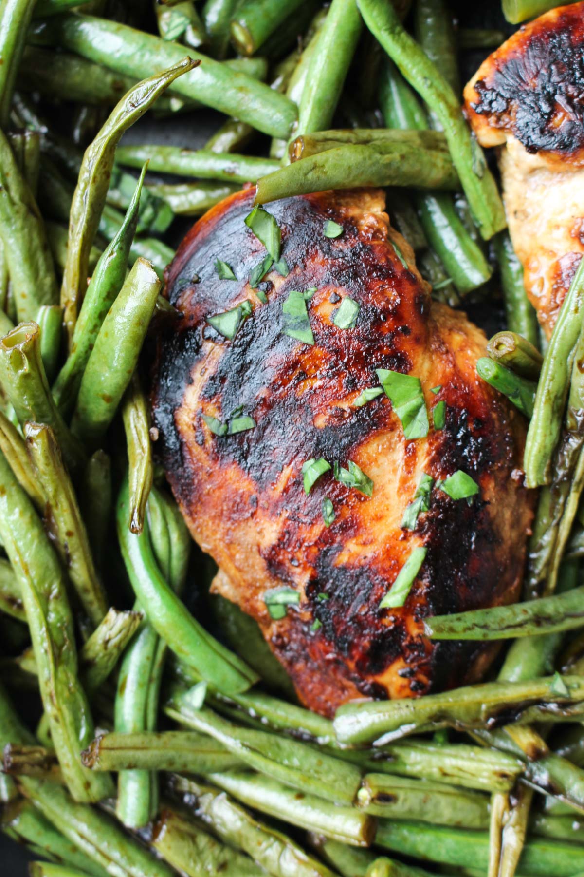 Close up shot of crispy balsamic chicken in the pan with fresh green beans.