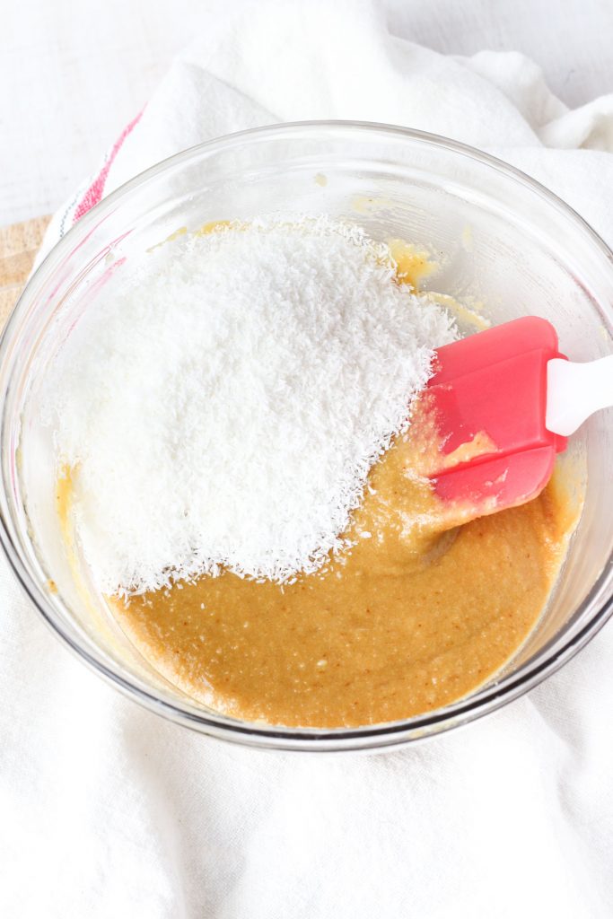 caramel and shredded coconut in a bowl with a spatula ready to fold them together.