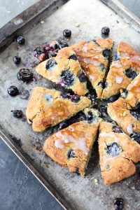 Pan of blueberry coconut scones with smashed blueberries around them, and a sweet drizzle on top!