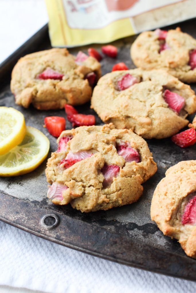 Paleo Strawberry Biscuits cooling on baking tray with fresh lemons sliced on the side.