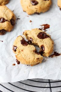 Chocolate chip cookies broken in half on parchment paper.