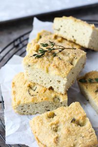 Bread sliced on parchment paper with fresh rosemary on top.