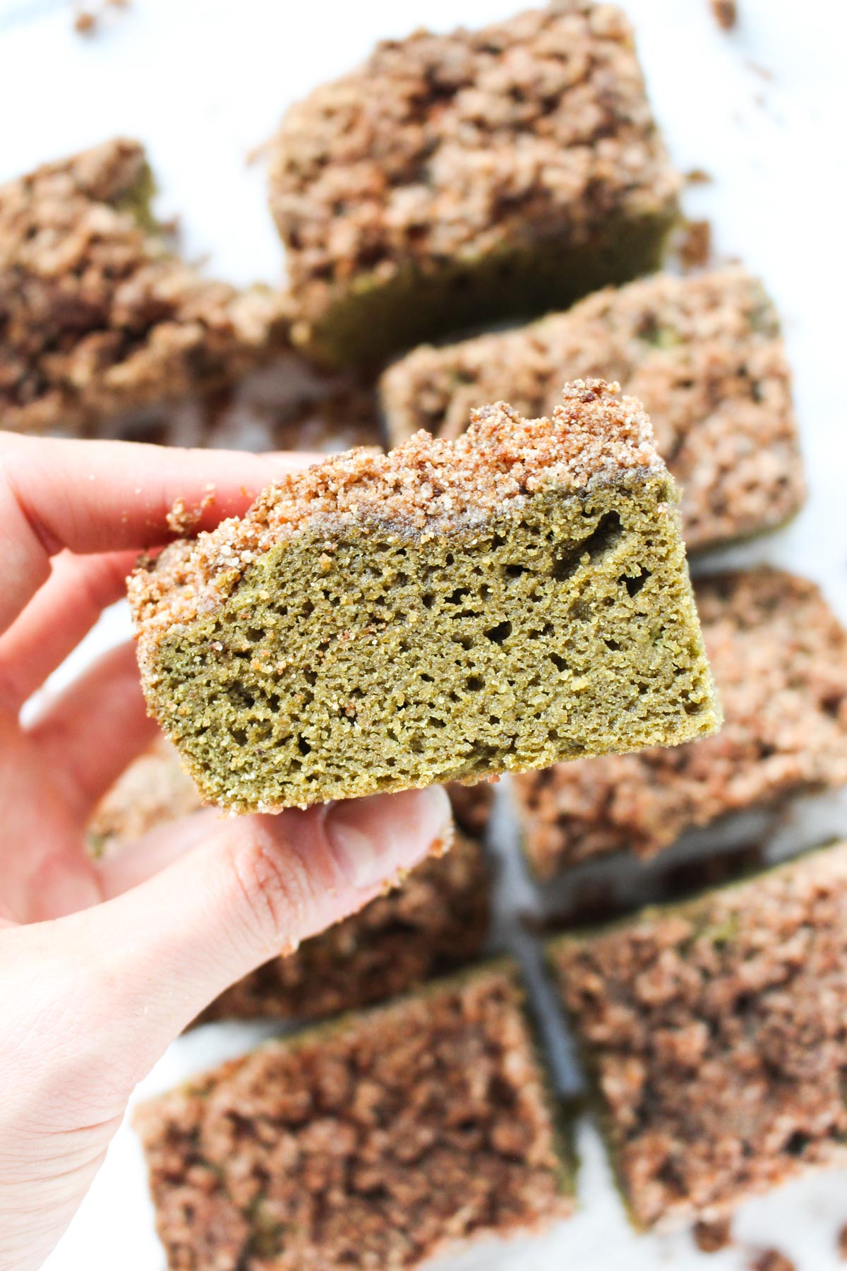 Hand holding up slice of matcha cake.