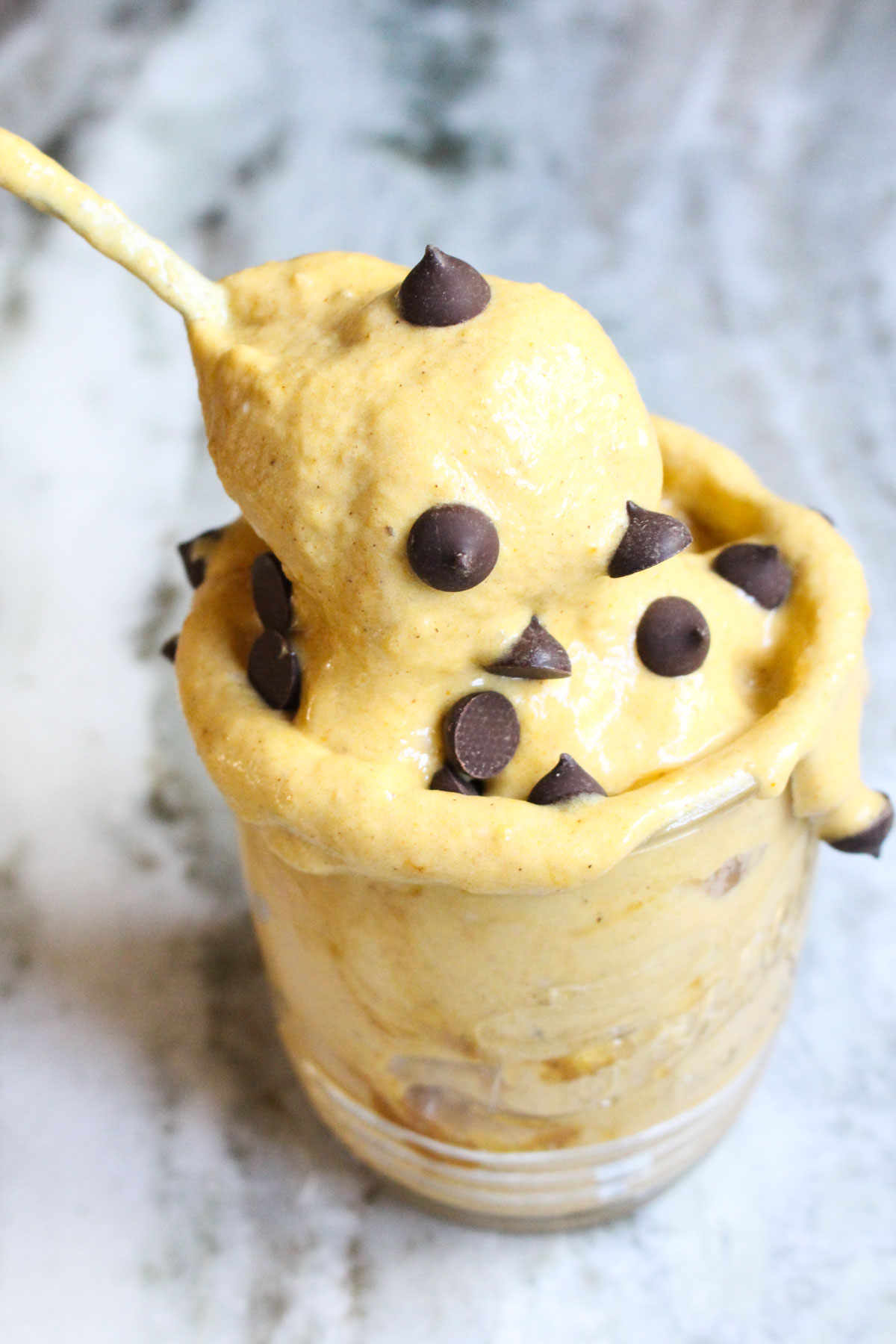 Spoon scooping out ice cream from the mason jar with chocolate chips on top.