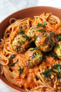 Close up shot of meatballs with sauce and spaghetti.