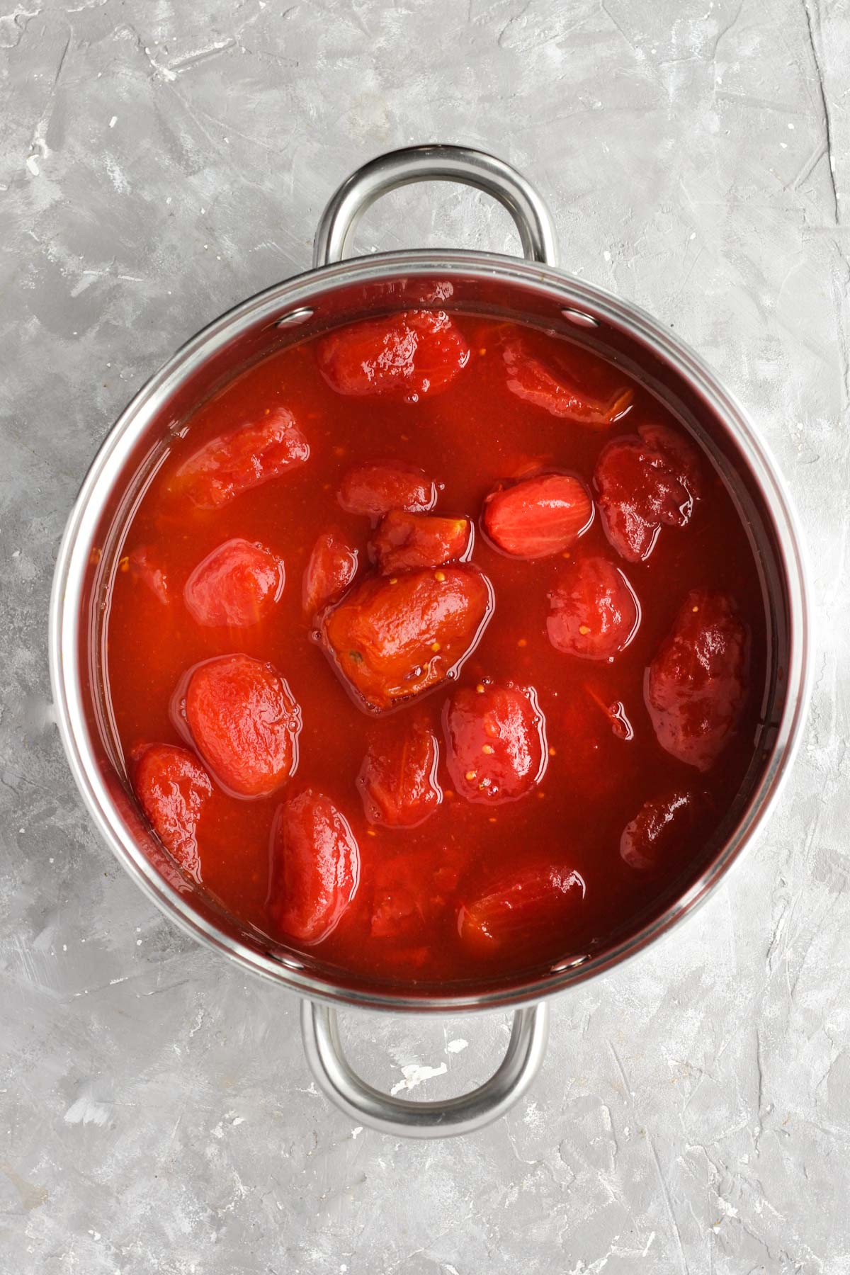 Whole peeled tomatoes in sauce pan.