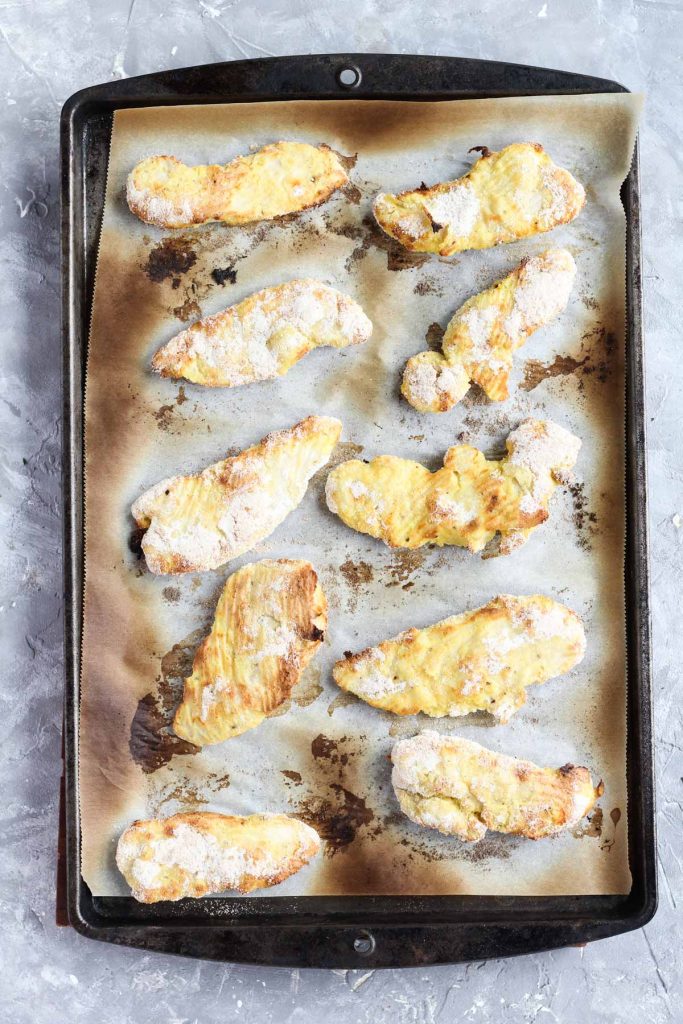 Chicken tenders on baking sheet after coming out of the oven.