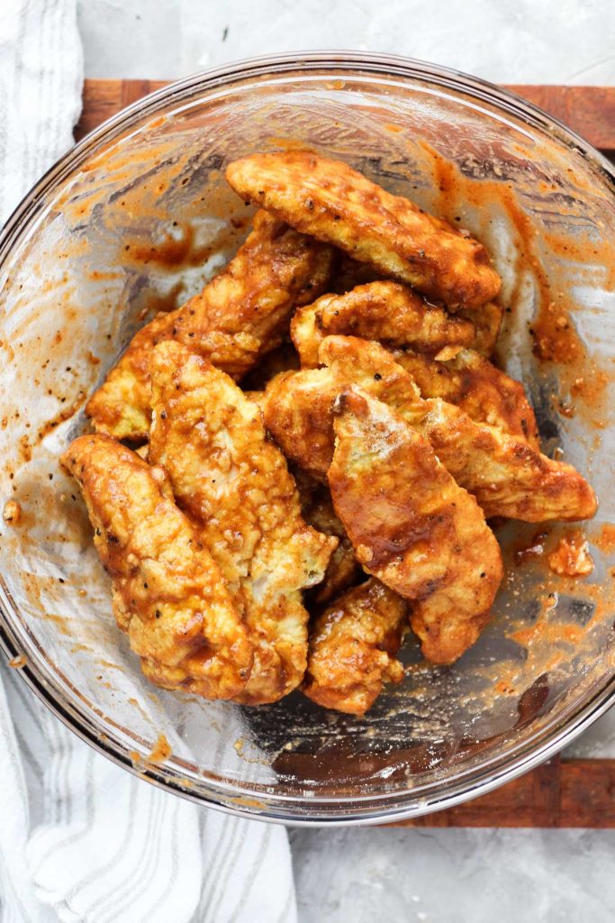 Bowl of chicken tenders tossed in BBQ sauce.