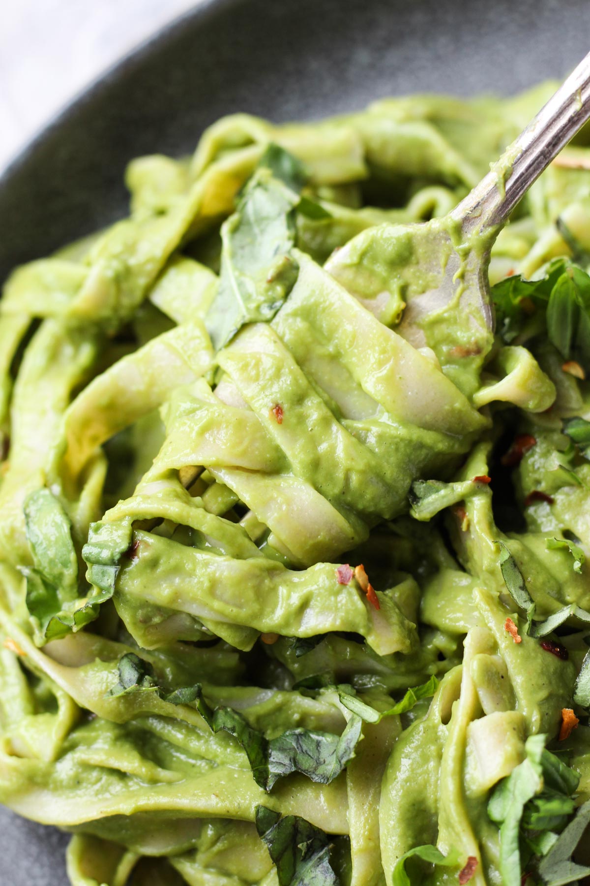 Fork twirling fettuccine with fresh pesto.