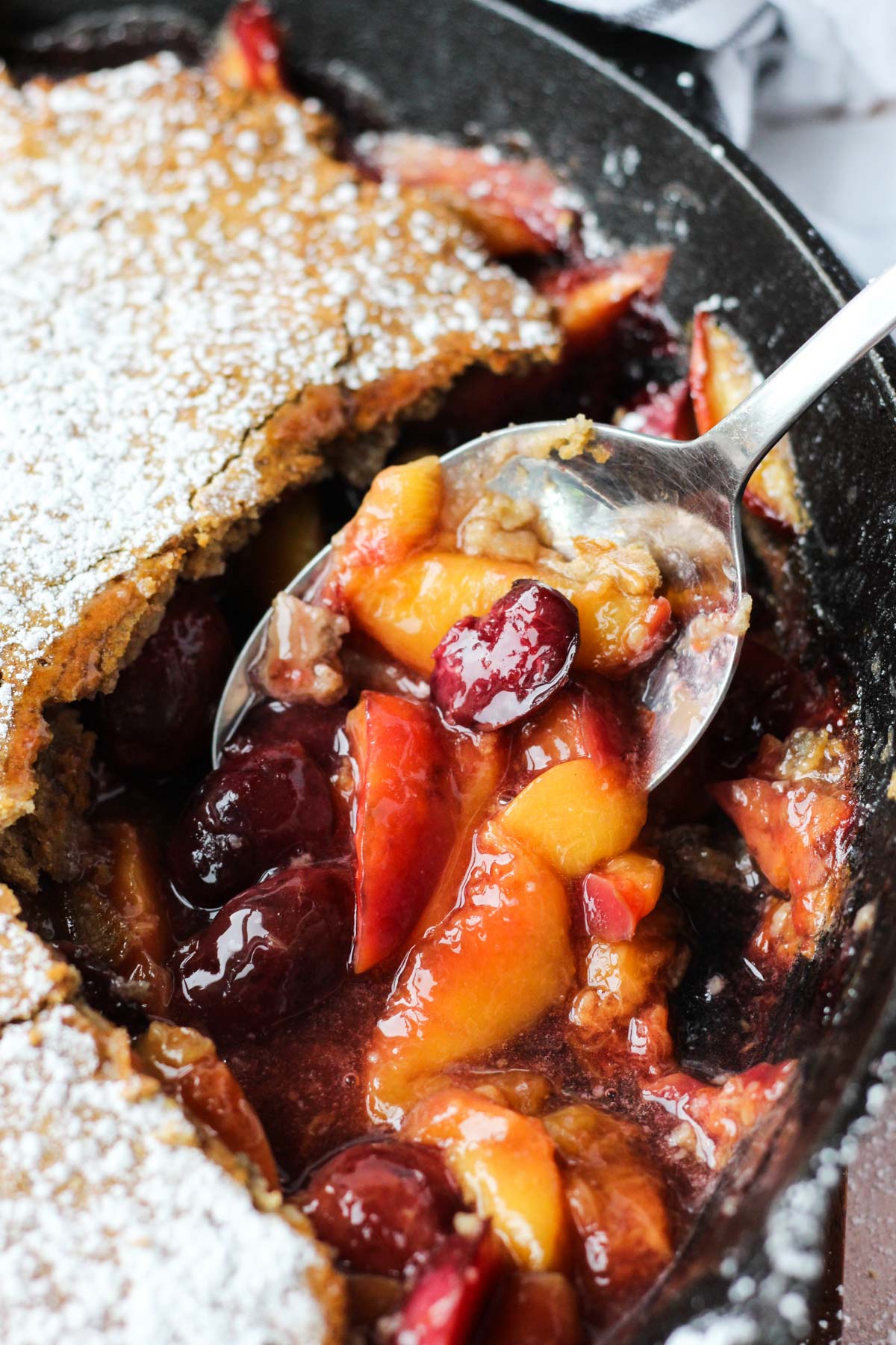 Spoon scooping out cobbler fruit.