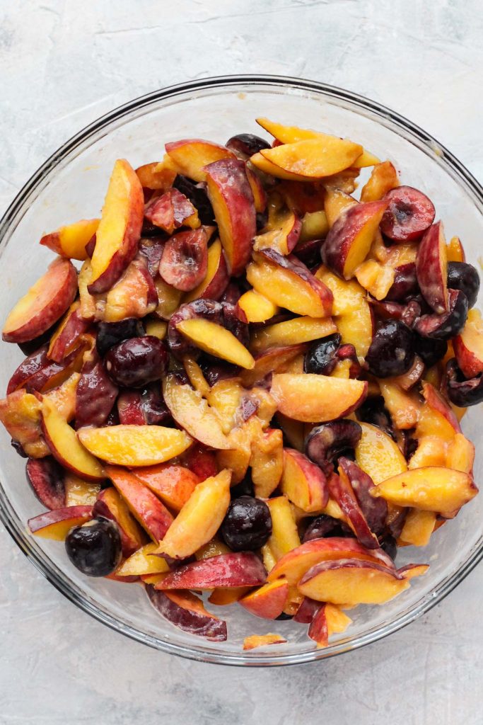 Fruit tossed with tapioca flour in glass bowl.