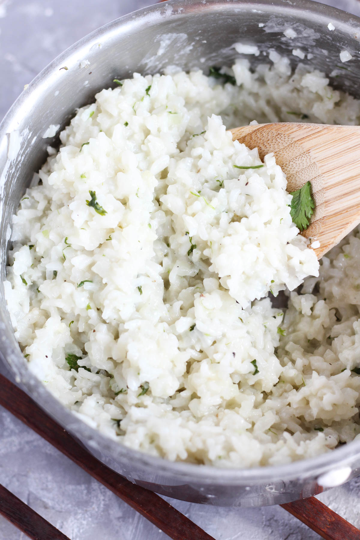Spoon scooping out cilantro rice from sauce pan.