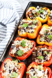Grilled stuffed peppers lined up on a baking sheet.