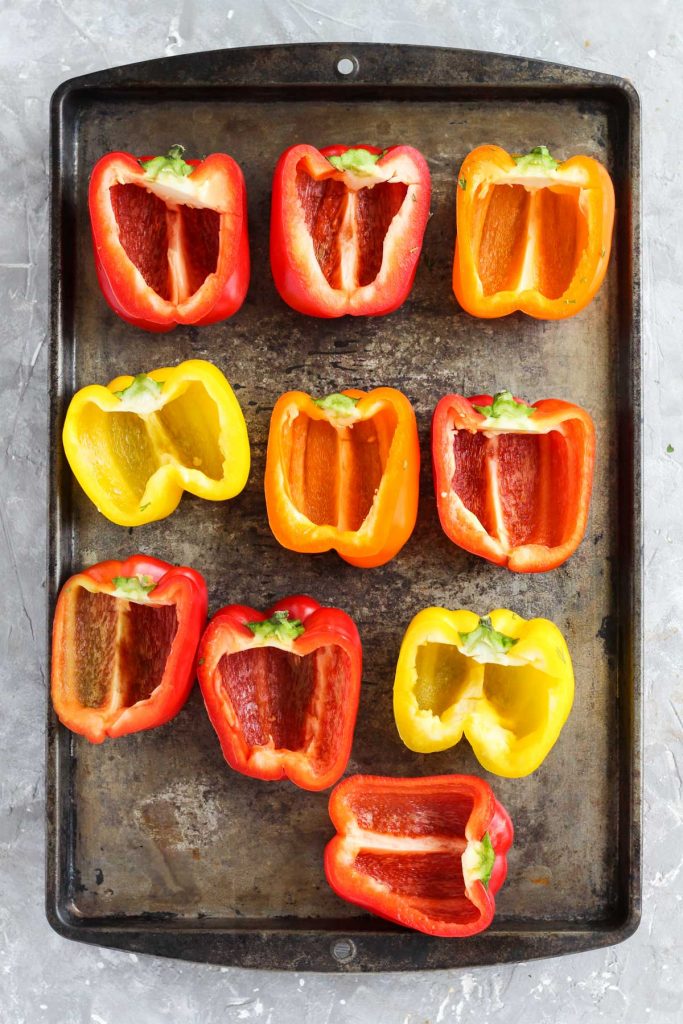 Peppers sliced in half on baking sheet.