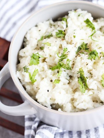 Cilantro rice in a ceramic bowl with fresh cilantro on top.
