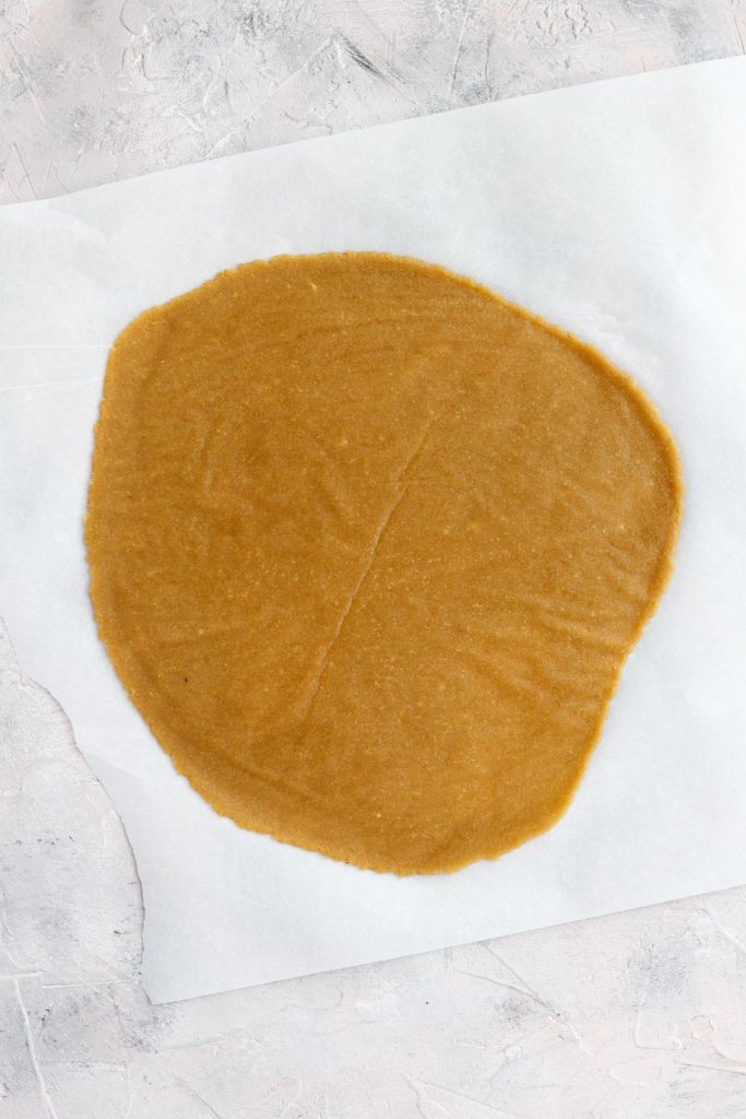 Pastry dough rolled out on parchment paper.