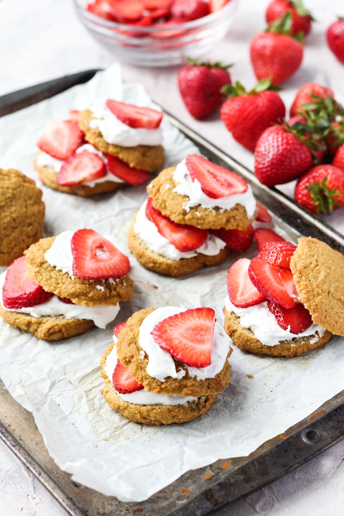 Strawberry shortcake lined up on a tray with fresh strawberries on the side.