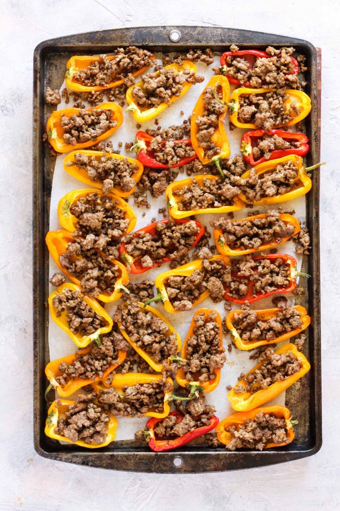 Peppers stuffed with meat on baking sheet.