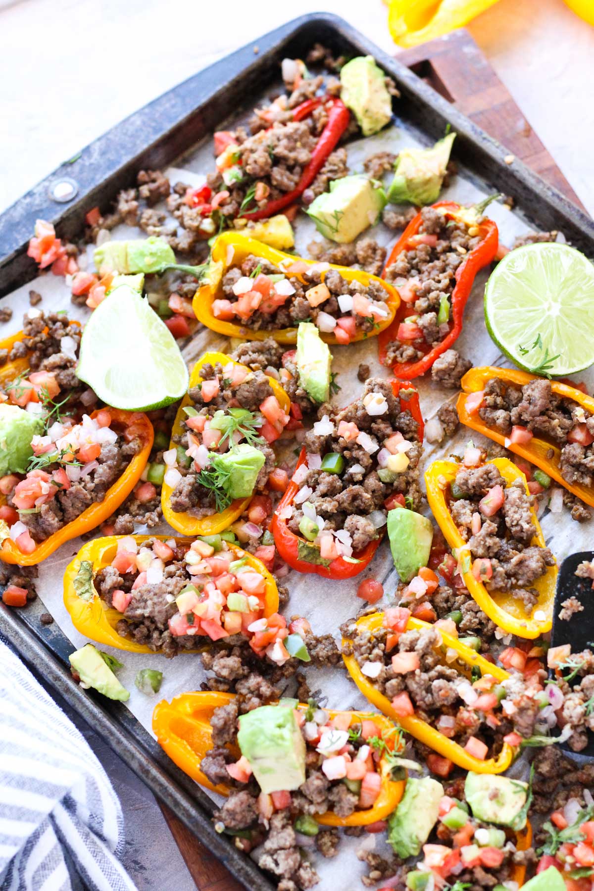 Finished pepper nachos on baking sheet with limes and cilantro.