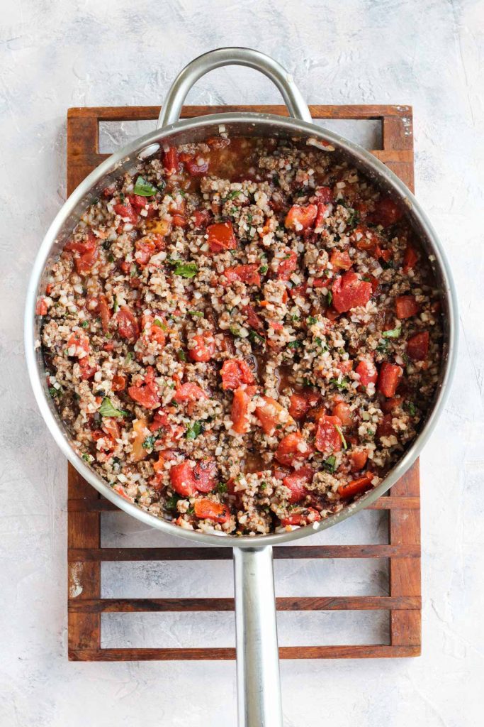 Ground beef with herbs and sauce in pan.