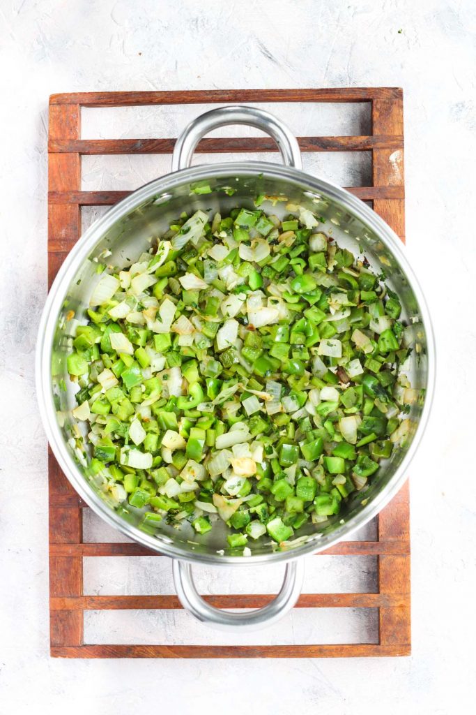 Onions, garlic, green peppers, and cilantro sautéing in pot.