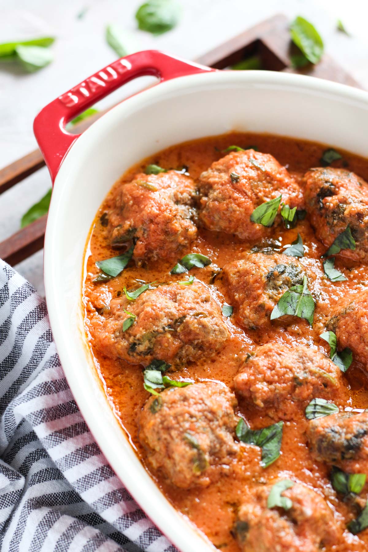 Close up of meatballs with sauce and fresh basil on top.