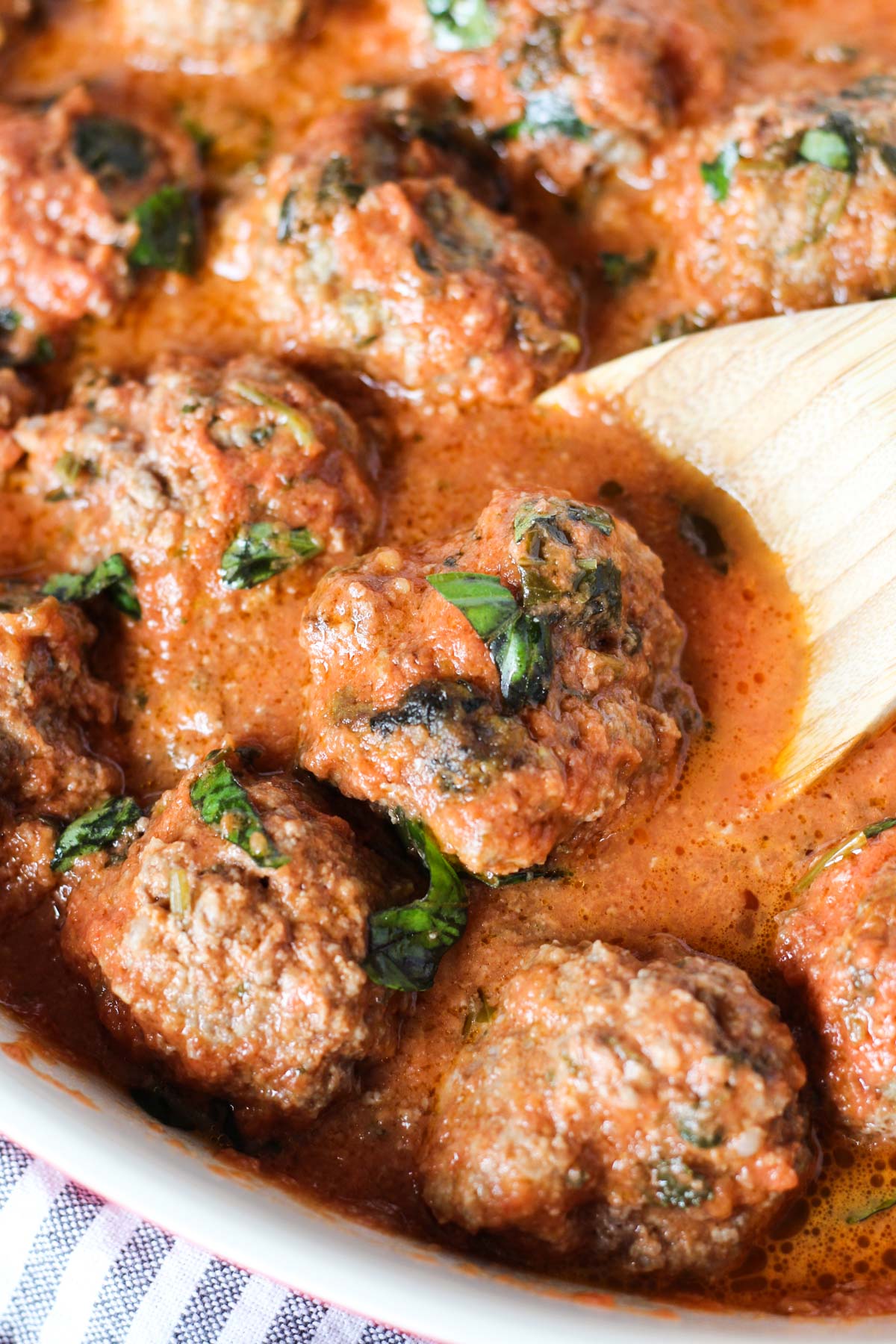 Close up picture of wooden spoon scooping out meatball.