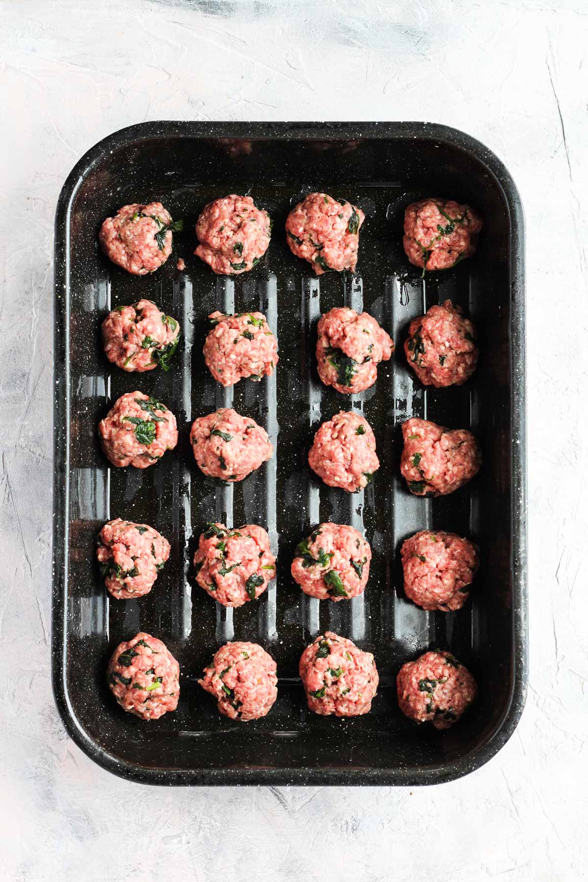 Meatballs rolled out and placed in a large baking dish.
