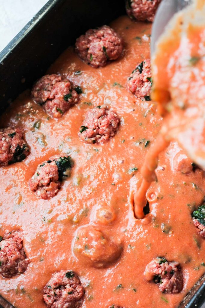 Sauce being poured over meatballs.