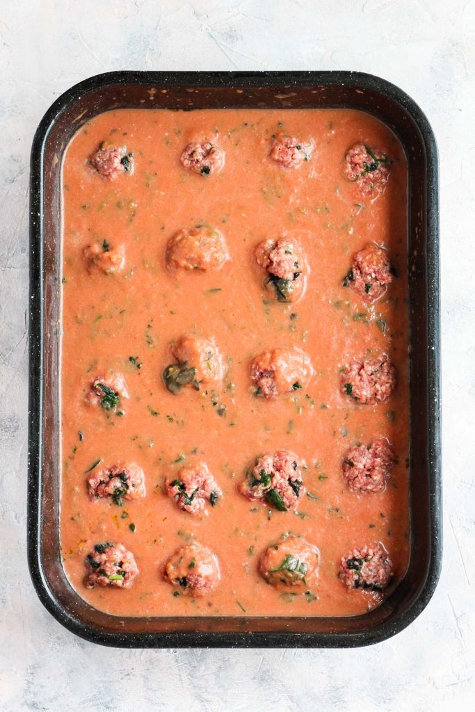 Meatballs and sauce in large baking dish.