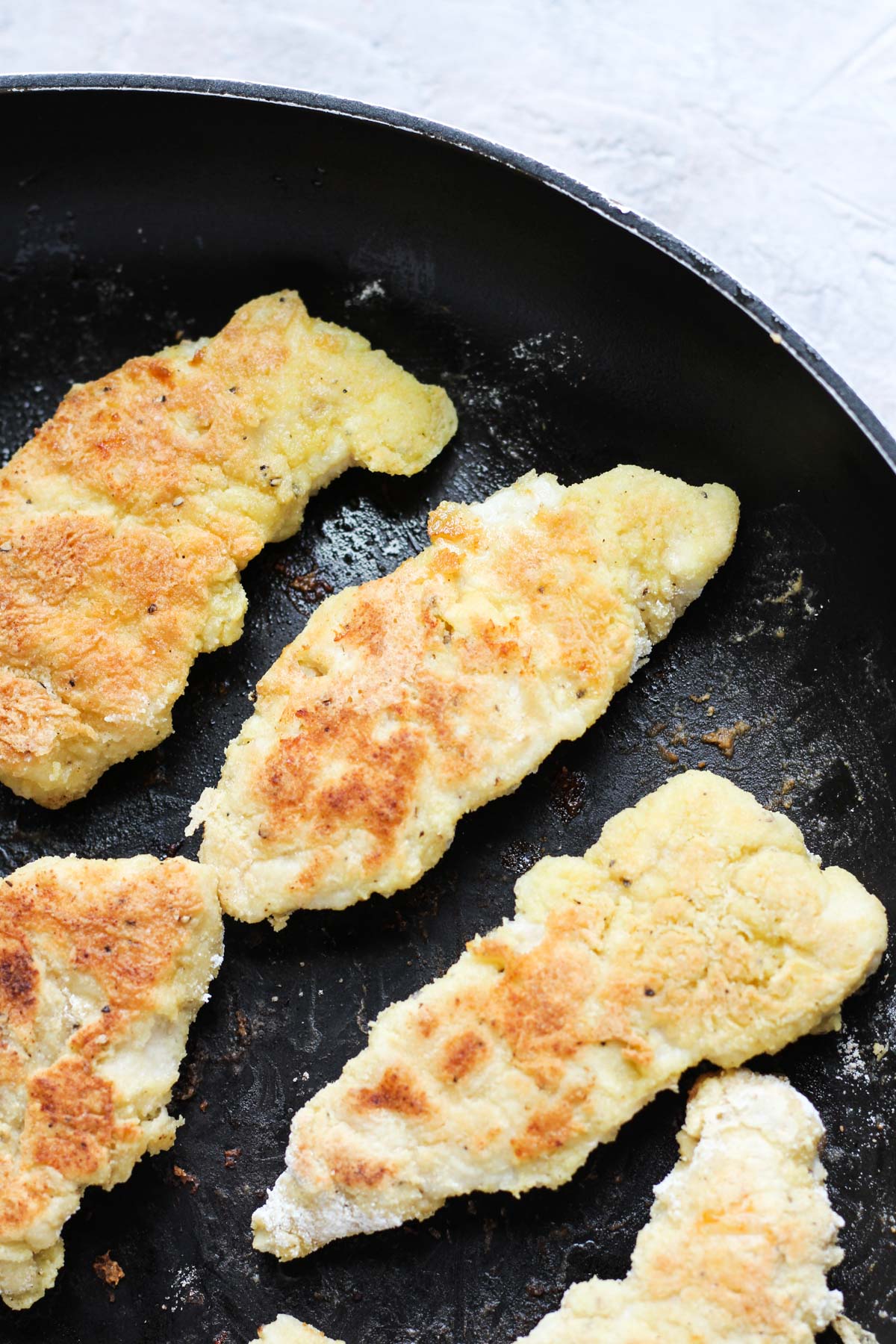 Chicken cutlets in frying pan.
