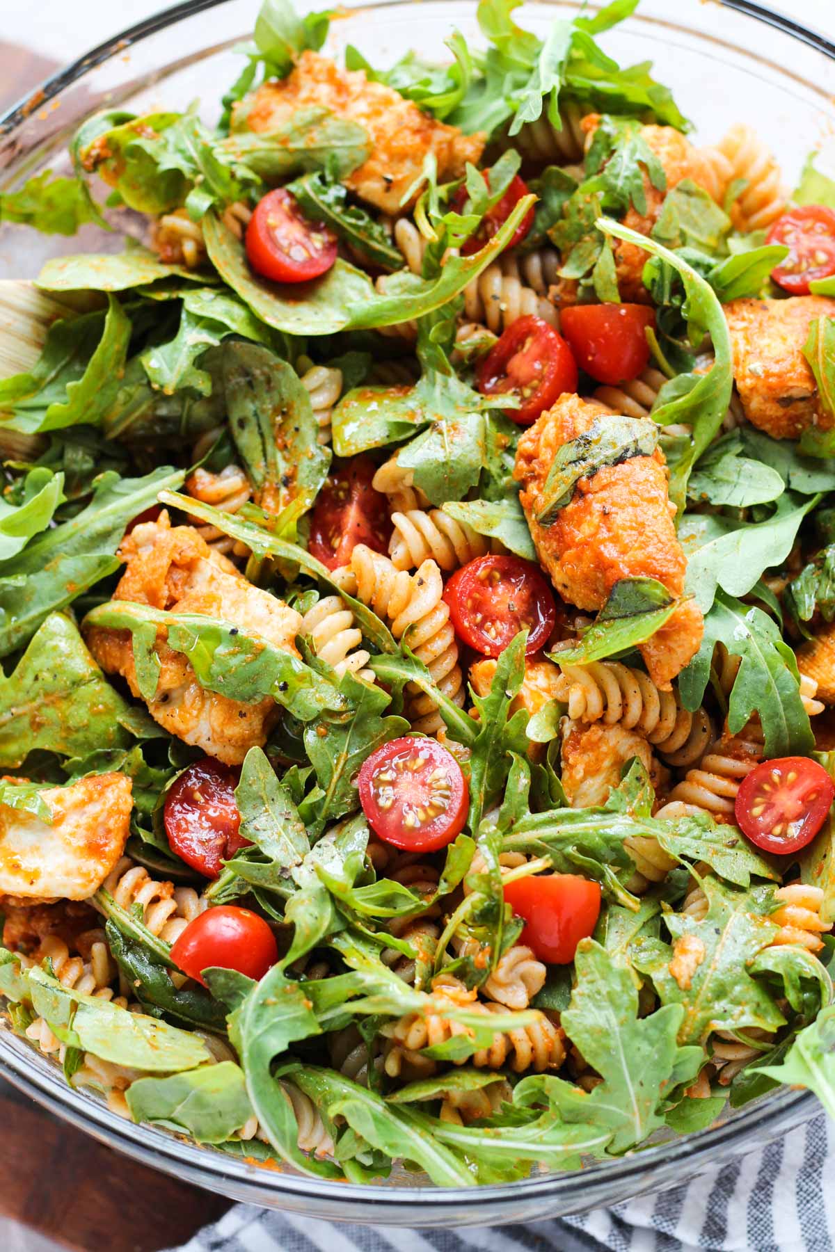 Close up shot of pasta salad with fresh grape tomatoes on top.