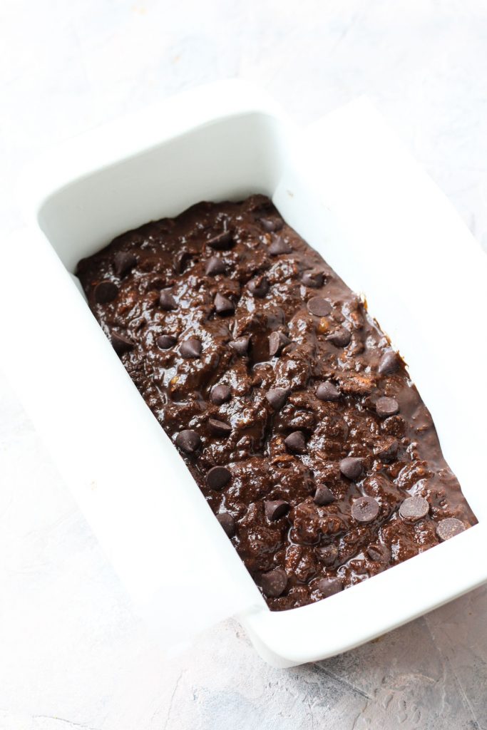 Banana bread batter in a parchment paper lined bread pan.