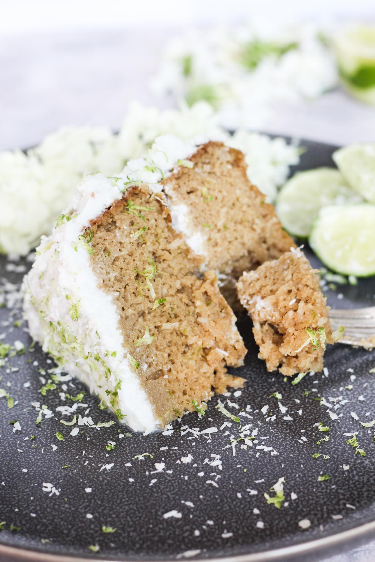 Slice of coconut lime cake on a grey plate.