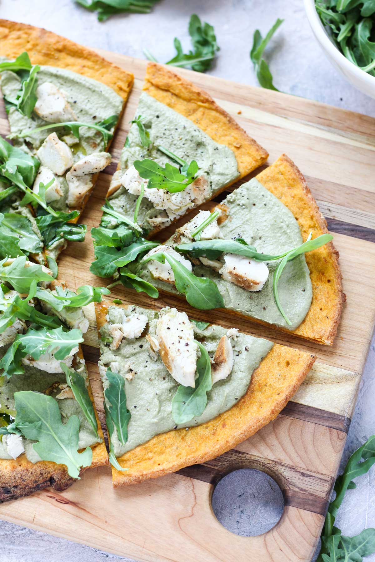 Pesto pizza on cutting board.