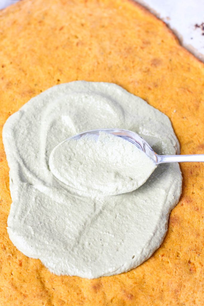 Spreading pesto on pizza crust.