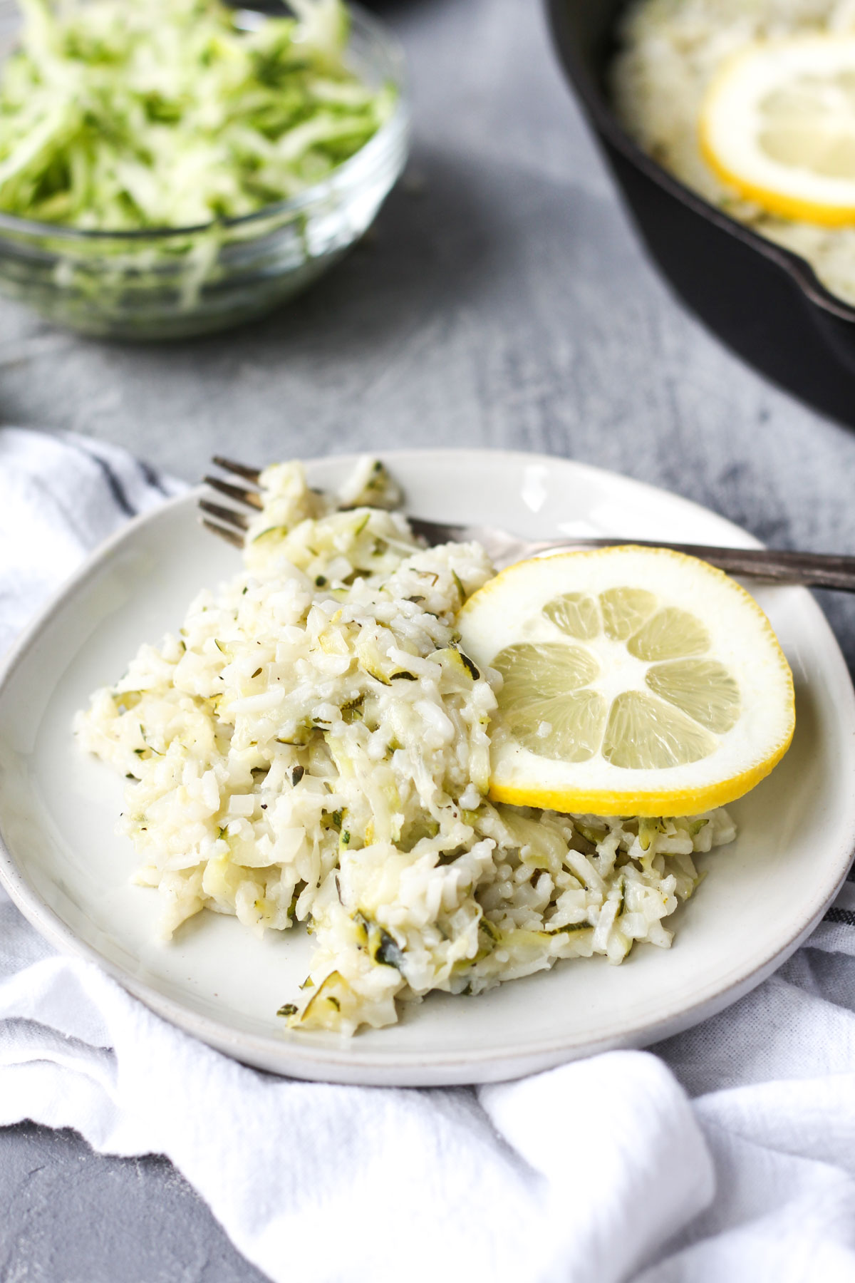 Plate of zucchini lemon risotto with shredded zucchini in the background.