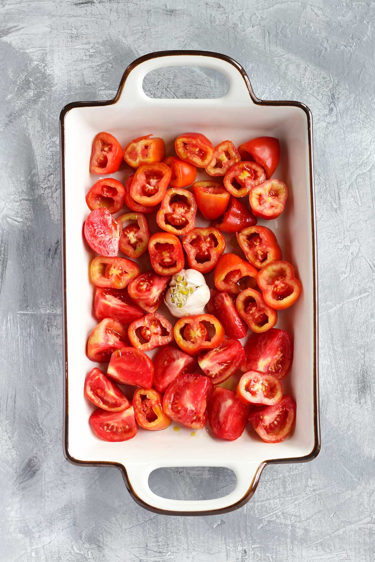 Tomatoes and garlic in a roasting pan.