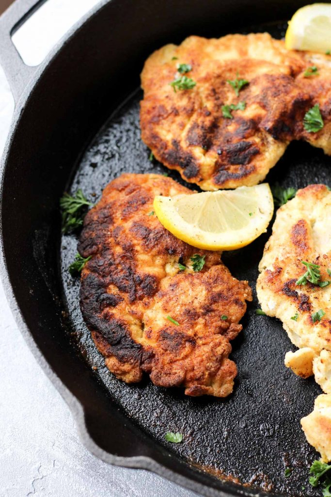 Chicken cooking in cast iron skillet.