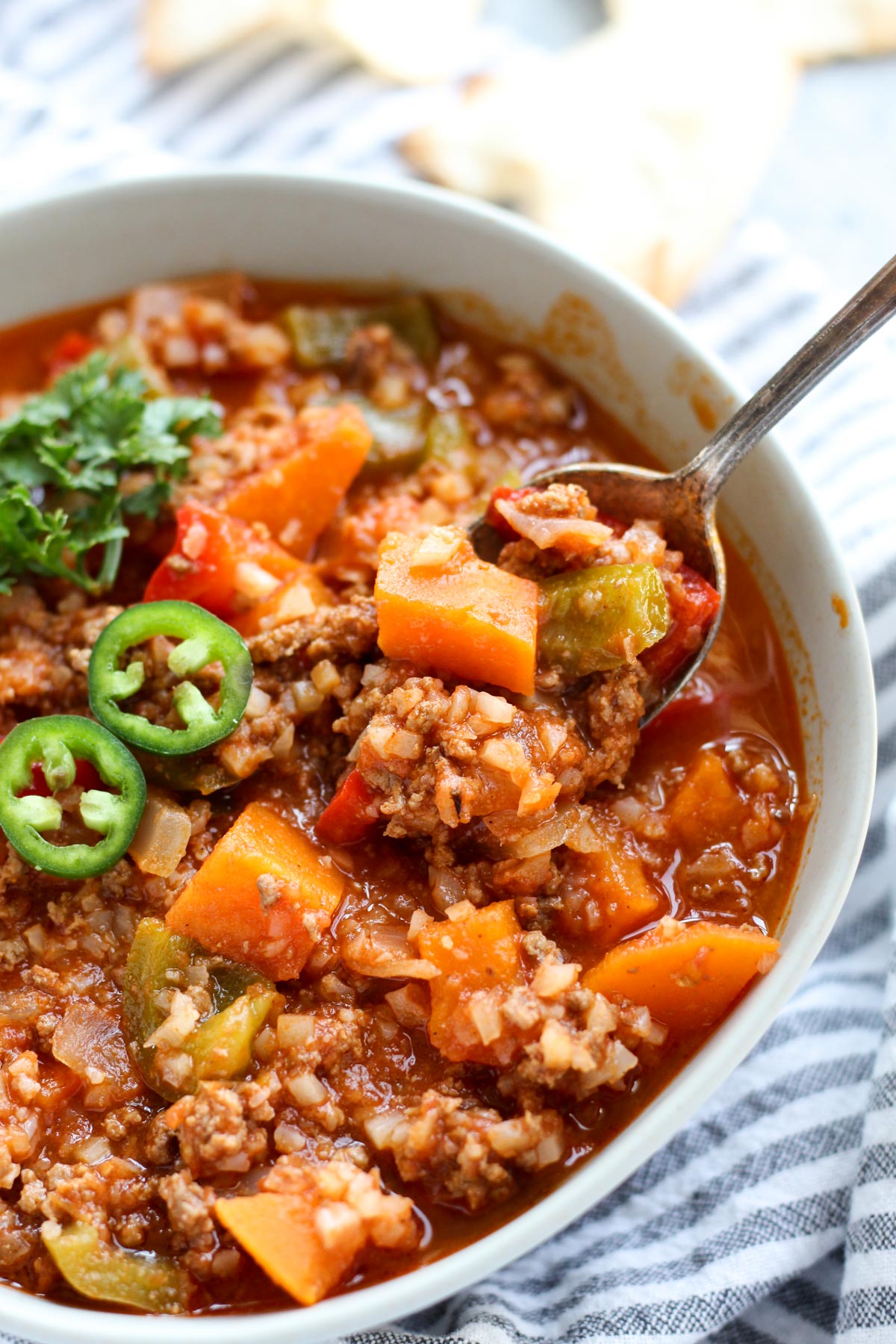 Spoon scooping out chili from bowl.