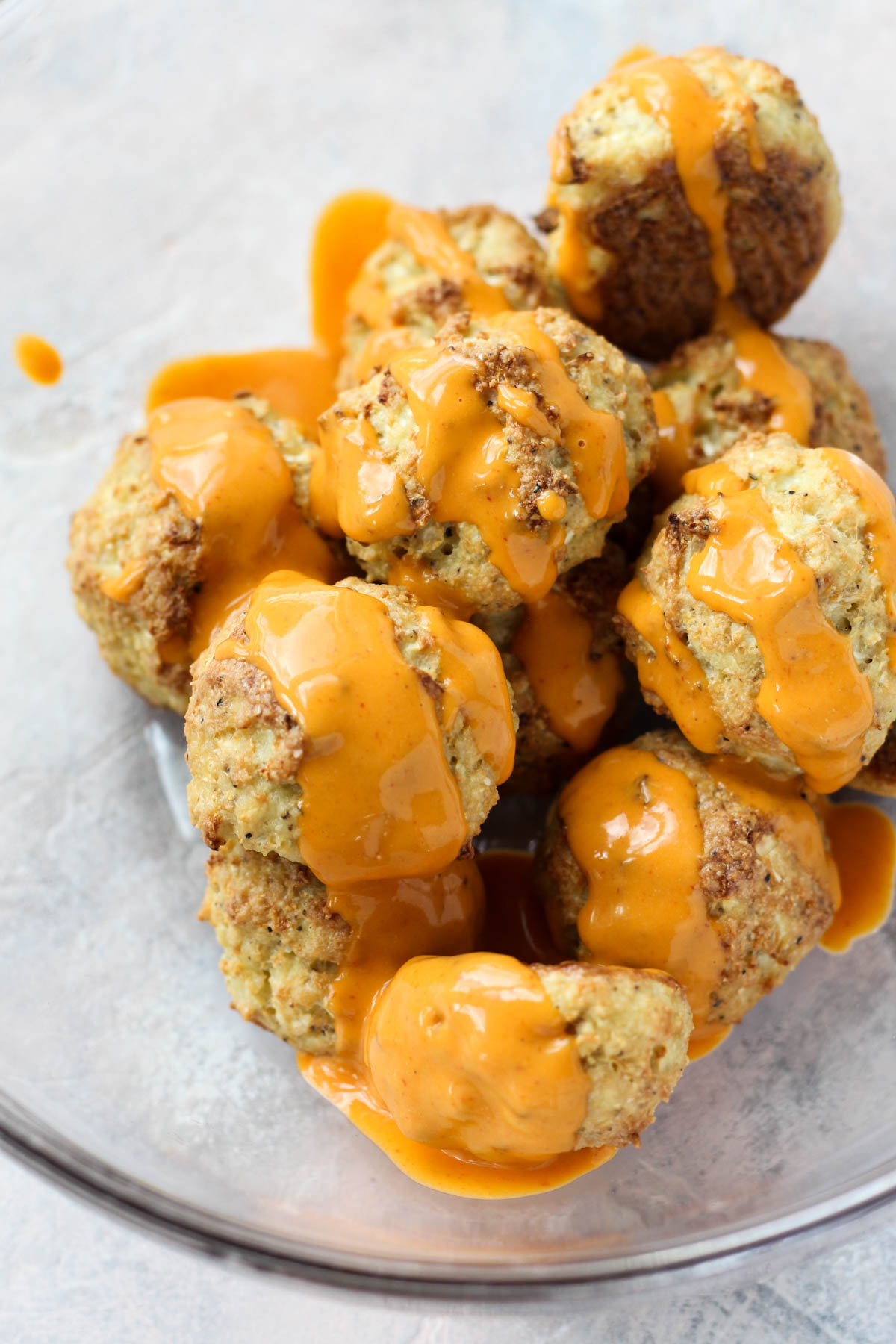 Buffalo sauce drizzled on meatballs.