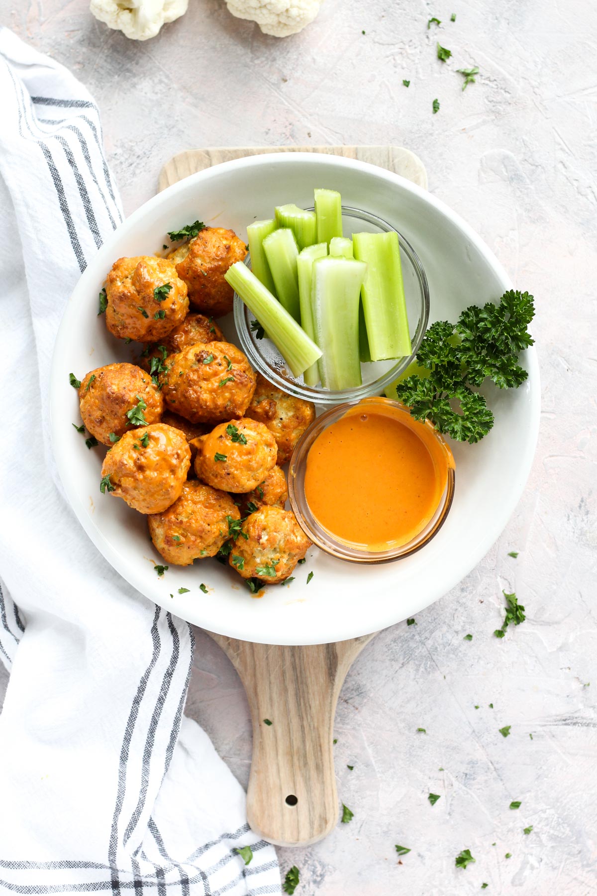 Overhead shot of meatballs in a bowl with celery and buffalo sauce.