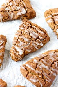 Pumpkin spice scones on parchment paper with a glaze on top.