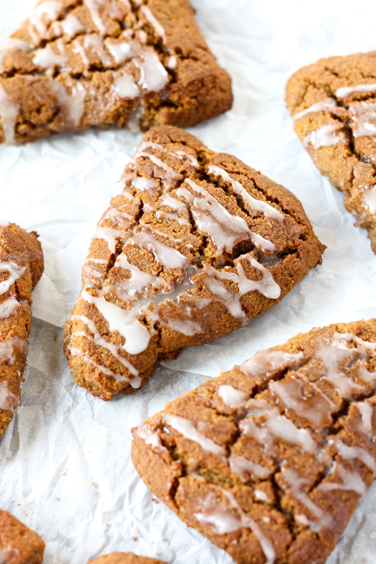 Pumpkin spice scones on parchment paper with a glaze on top.