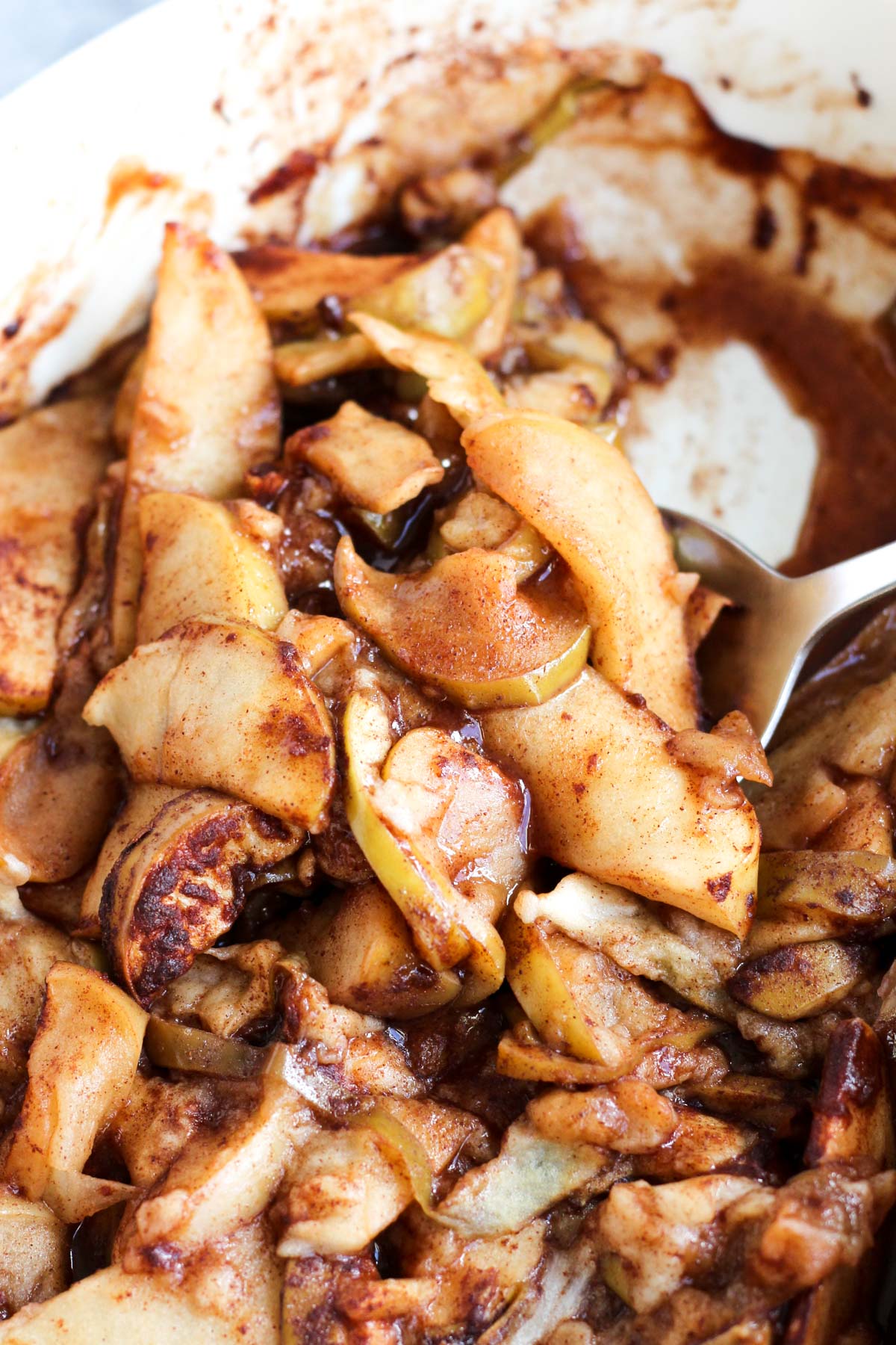 Spoon scooping out baked apple slices.
