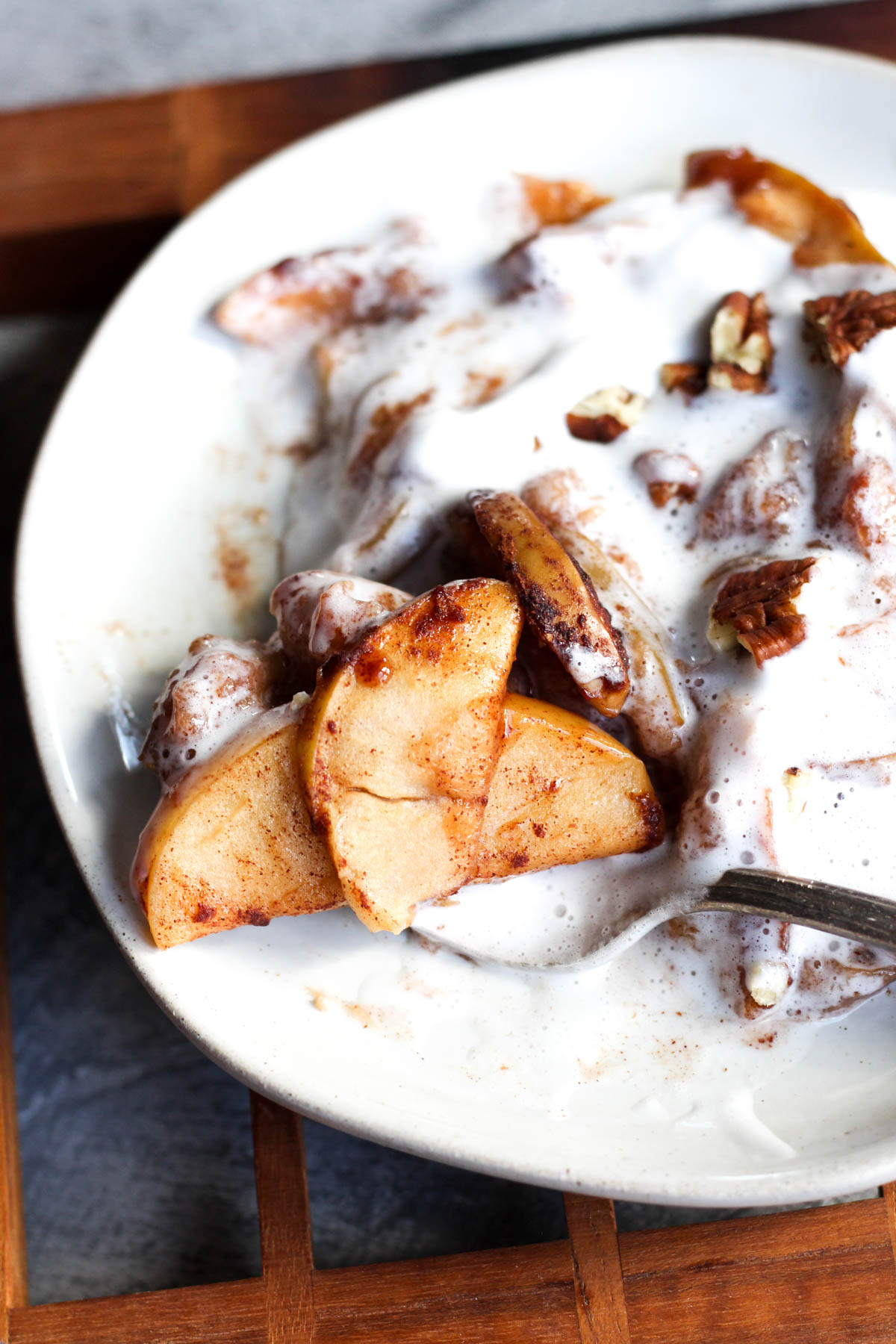 Plate of baked cinnamon apples with coconut whipped cream on top.