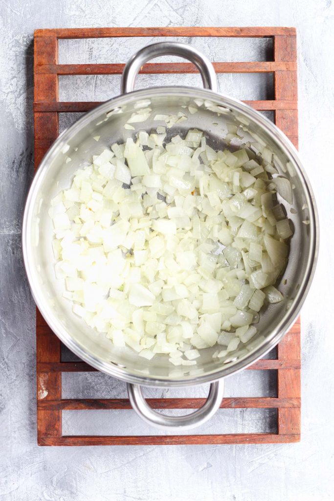 Onions and garlic sautéing at the bottom of a soup pot.